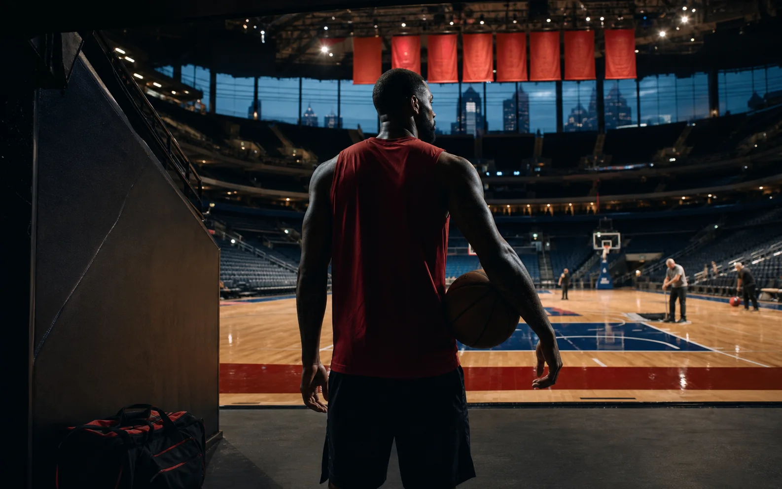 Basketteur vétéran en tenue rouge entrant sur le parquet sombre d’une grande salle de Philadelphie